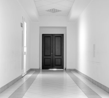 White hallway with marble floor and brown door in hospital black and white