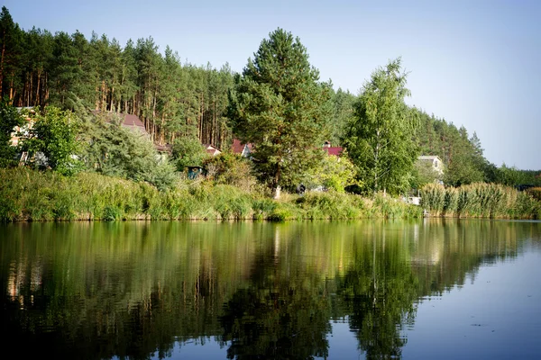 Casa do rio com reflexos e céu azul perto da floresta alta contrastado com efeito vinheta — Fotografia de Stock