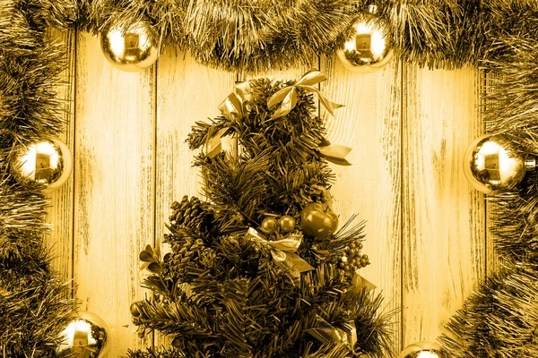 New year theme christmas tree with decoration and balls on white retro stylized wood background golden filtered — Stok fotoğraf