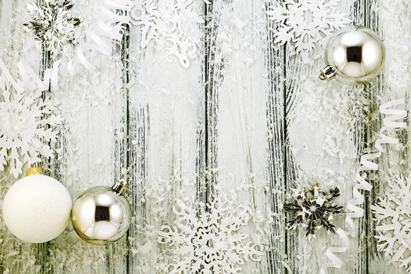 Tema de Año Nuevo: Árbol de Navidad decoraciones blancas y plateadas, bolas, nieve, copos de nieve, serpentina sobre fondo de madera estilizada retro blanco con luz de fondo amarilla — Foto de Stock