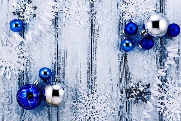 Tema de Año Nuevo: Árbol de Navidad decoraciones blancas y plateadas, bolas azules, nieve, copos de nieve, serpentina sobre fondo de madera estilizada retro blanco con luz de fondo azul — Foto de Stock