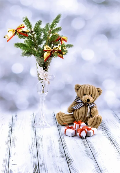 Árbol de Navidad en copa decorativa blanca, caja de regalo blanca y roja, oso de juguete marrón y nieve sobre mesa blanca vintage retro aislada sobre fondo azul borroso — Foto de Stock