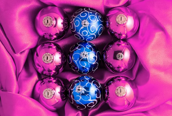Background of pink and blue Christmas tree balls on pink shiny silk fabric — Φωτογραφία Αρχείου