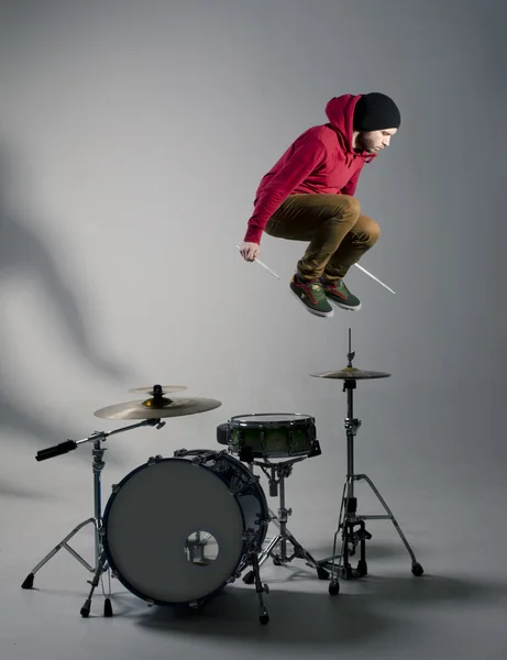 Joven baterista saltando mientras toca Imágenes de stock libres de derechos