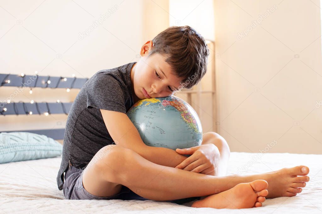 Young boy holding world in the palm of his hands concept for education, travel, communications, politics or environmental conservation.