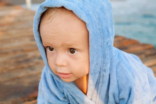 水泳の後にタオルのローブに包まれたビーチで休んでいるかわいい男の子 夏のビーチバケーションのコンセプト — ストック写真