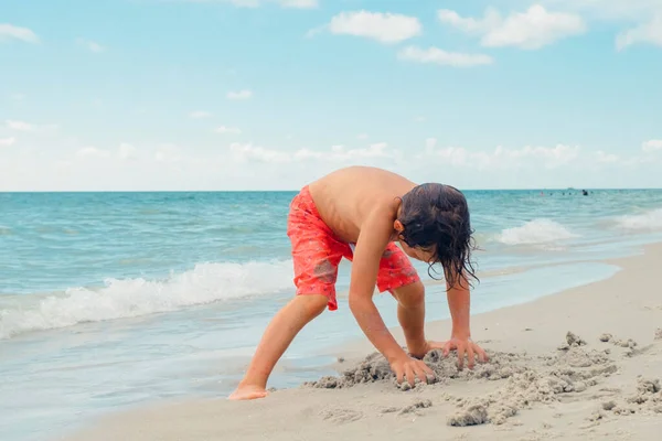 子供は熱帯のビーチで遊ぶ 子供は夏休みに海で遊ぶ 子供たちはビーチリゾートで楽しんでいます 面白い少年は砂の上に書き込みます アクティブ子供のライフスタイル 水泳の人々 — ストック写真