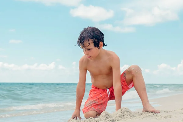 子供は熱帯のビーチで遊ぶ 子供は夏休みに海で遊ぶ 子供たちはビーチリゾートで楽しんでいます 面白い少年は砂の上に書き込みます アクティブ子供のライフスタイル 水泳の人々 — ストック写真