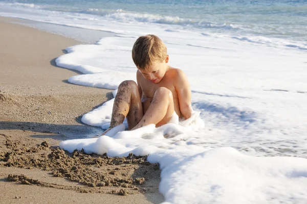 Ragazzo che gioca sulla spiaggia in acqua — Foto Stock