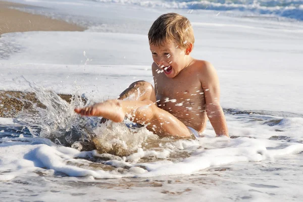 Ragazzo che gioca sulla spiaggia in acqua — Foto Stock