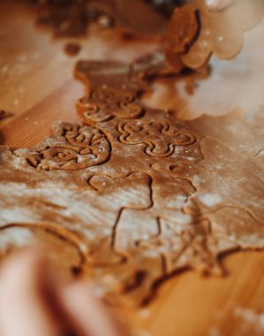 Kalpler, yıldızlar ve hayvanlar da dahil olmak üzere çeşitli şenlik şekilleri kesilmiş un kaplı zencefilli ekmek hamuru yakın plan. El yapımı Noel kurabiyeleriyle dolu sıcak tatil pişirme atmosferi.