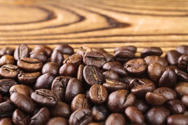 Ahşap masa üzerinde kavrulmuş kahve fasulye arabica, yakın çekim, seçici odak