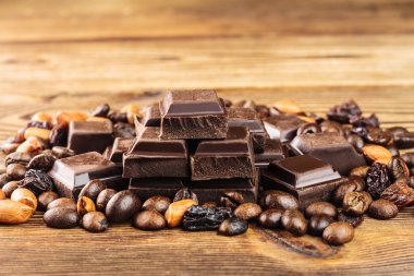 Koyu çikolata küpleri, kahve çekirdekleri, fıstık ve üzüm ahşap tablo, yakın çekim