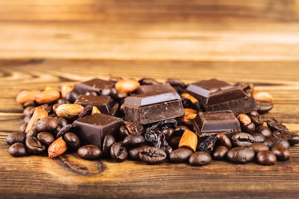 Koyu çikolata küpleri, kahve çekirdekleri, fıstık ve üzüm ahşap tablo, yakın çekim