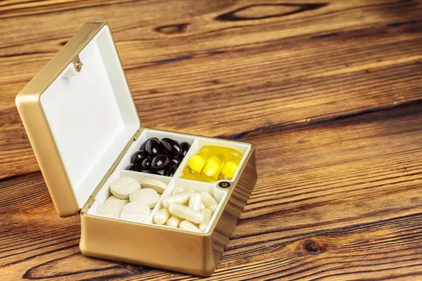 Karışık doğal gıda takviyesi konteyner, omega 3, c vitamini, ahşap arka plan üzerinde karoten kapsül hap