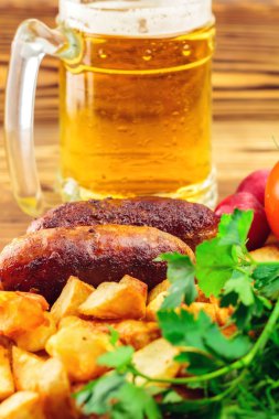 Izgara et sosis kızarmış patates, taze ürünler ile kupa bira ahşap tahta üzerinde