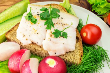 Dilim çavdar ekmeği, taze domuz domuz yağı ve plaka, taze maydanoz sandviçle üretmek, sebze, yakın çekim.