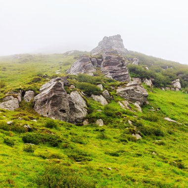 Karpat dağlarının bulutlu tepesinde kaya üzerinde görünümü, Ukrayna.