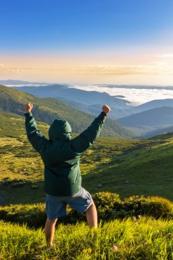 Dağ ve gösterileri başparmak yukarıya ve zafer duygu gündoğumu zaman, Karpatlar üstünde duran genç adam.