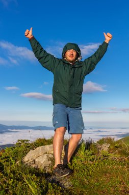 Dağ ve gösterileri başparmak yukarıya ve zafer duygu gündoğumu zaman, Karpatlar üstünde duran genç adam.