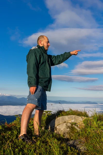 Genç dağ tepesinde duran adam ve parmak uzakta gündoğumu zamanında, Karpatlar göster.