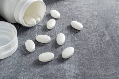 Beyaz haplar ve dokulu gri arka plan, ilaçlar, antibiyotik, kalsiyum, ağrı kesici, vitamin takviyeleri yakın çekim görüntüsü..