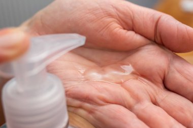 Üst düzey kadın elleri dezenfeksiyon için dezenfekte jeli kullanır ve koronavirüsü, Covid-19 enfeksiyonunu önler, antibakteriyel antiseptik ile avuç içi temizler, yakın çekim görüntüsü verir..