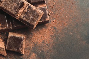 Çikolata ve dilimlenmiş çikolata. Arka planda koyu renk ve fotokopi alanı var..