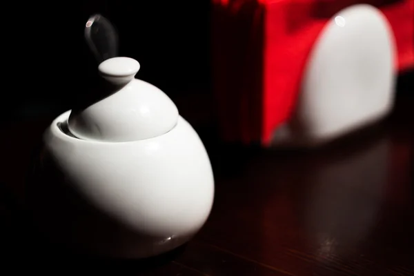 Белая сахарная чаша и красные салфетки на темном деревянном столе — стоковое фото