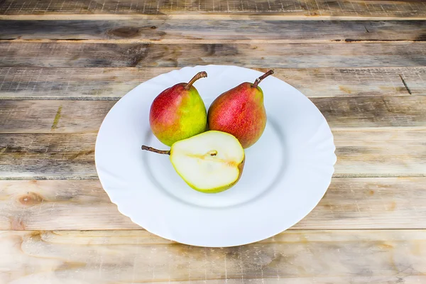 Two and half pears in white plate, rustic wooden table — Stock Photo, Image