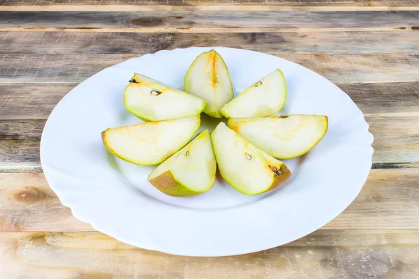Sliced fresh pears in white plate on rustic wooden table — Stock Photo, Image