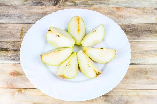 Sliced fresh pears in white plate on rustic wooden table — Stock Photo, Image