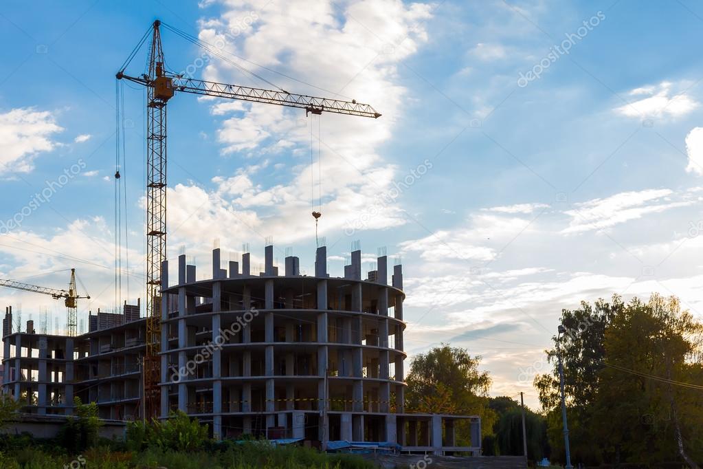 Crane and building construction on cloudy sky background