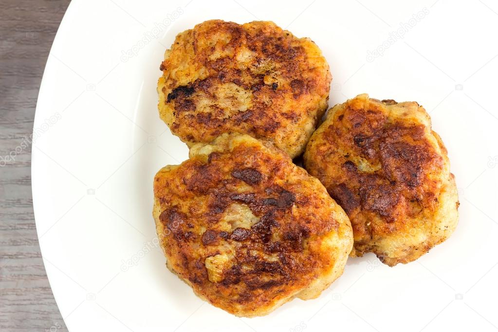 Fried meat cutlets on white plate, top view