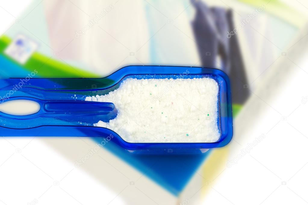 Laundry detergent or washing powder in blue measuring cup studio isolated
