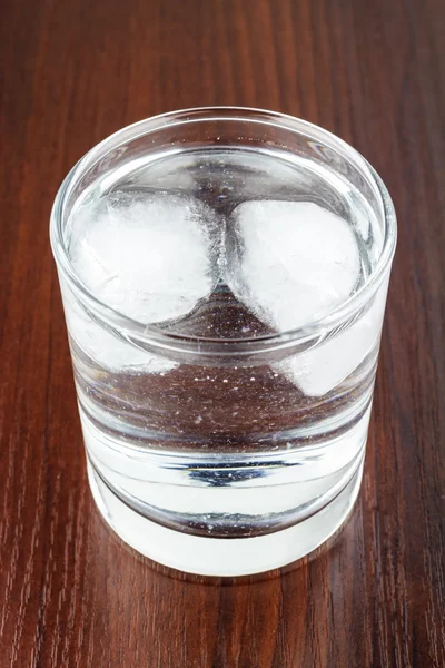 Ahşap masa üzerinde buz ile şeffaf arıtılmış su — Stok fotoğraf