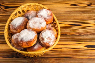 Ev yapımı taze çörek hasır sepet ahşap masa, metin için yer üzerine pudra şekeri serpilir