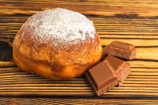 Ev yapımı taze çörek pudra şekeri ve küpleri ahşap masa üzerinde çikolata serpilir — Stok fotoğraf