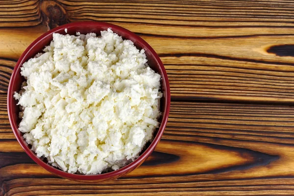 Fresh cottage cheese in ceramic bowl on wooden table, top view — Stok fotoğraf