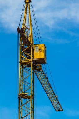 Mavi gökyüzünün altında sarı bina vinç