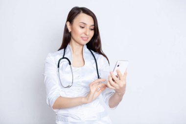 Kız, beyaz cüppeli bir doktor. Hastasına mesaj yazıyor ya da telefona cevap veriyor. Teletıp. Doktor hatta..