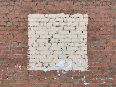 Duvarın ortasında çatlaklar olan kırmızı tuğla duvar bej rengi kare boyalı. 
