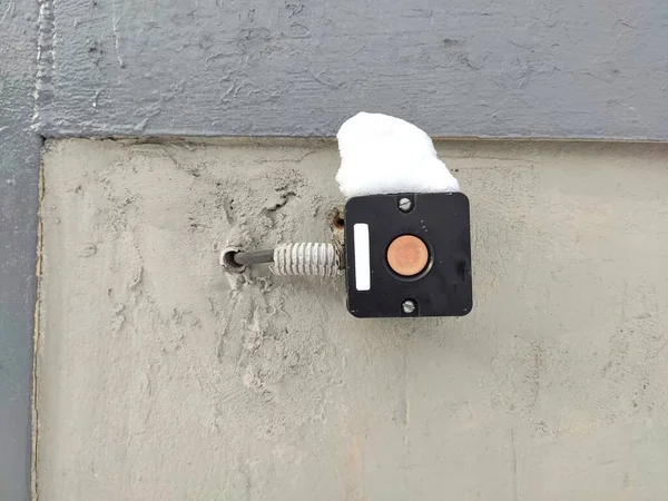 fragment of a wall with a black button for opening the gate