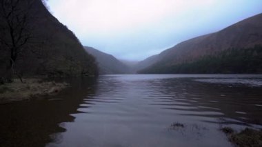Glendalough Co. 'daki Wicklow Irlanda Gölü' nün arka planında karlı dağlar var.