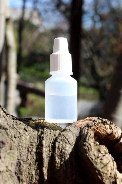 White clear medical bottle on a branch of a tree in the sunny day