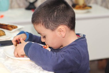 Küçük şirin bir çocuk yemek yiyor.