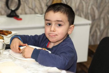 Küçük şirin bir çocuk elinde yemek tabağı tutuyor.