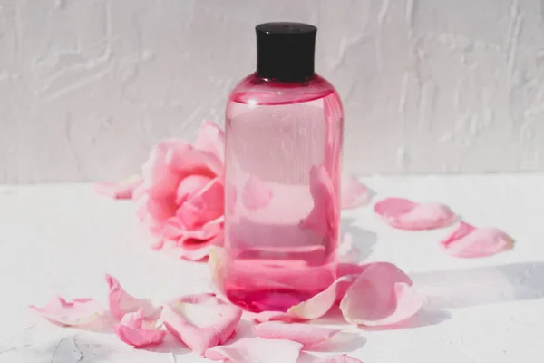 pink beauty product bottle surrounded by tender rose petals and