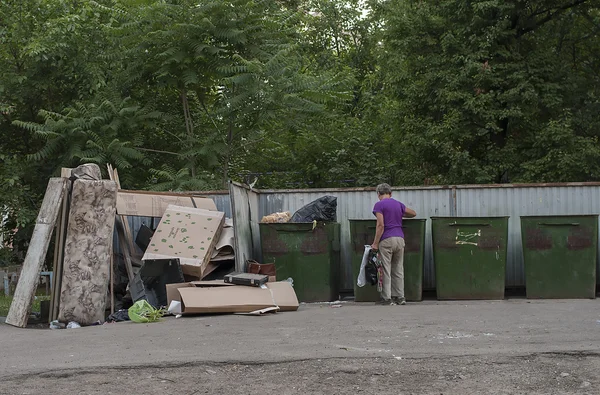 lonely man rummaging in a dumpster