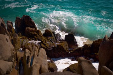 Yeşil dalgalar kahverengi kayalara çarpıyor.